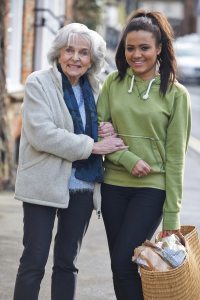 Teenage Girl Helping Senior Woman Carry Shopping