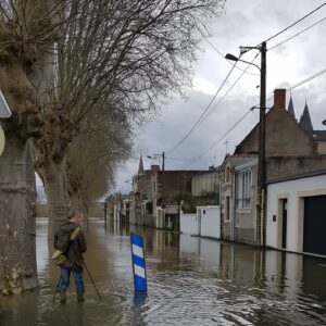 Photo : _Challones sur Loire, inondations. Un homme avec une perche essaye de déboucher l'eau dans une rue.